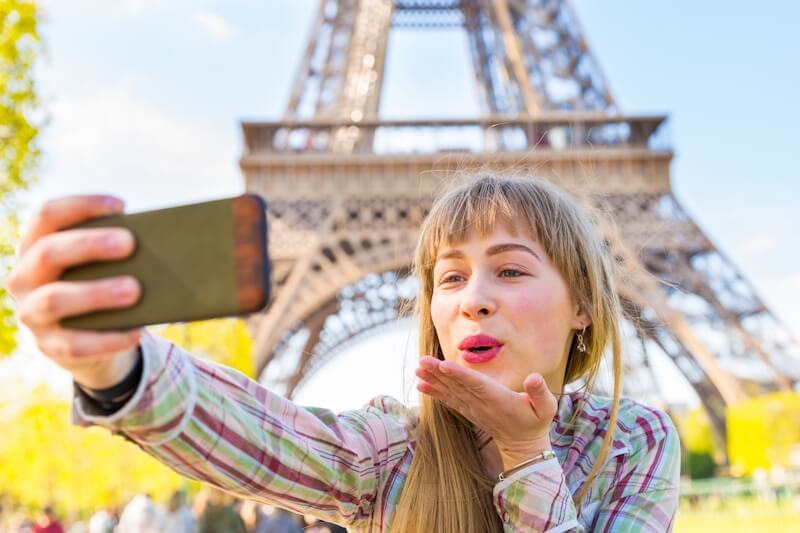 Tirando foto com o celular em frente à Torre Eiffel
